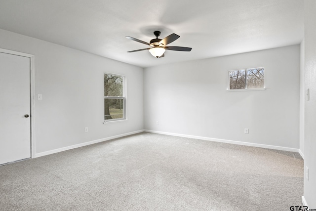 carpeted spare room featuring ceiling fan and baseboards