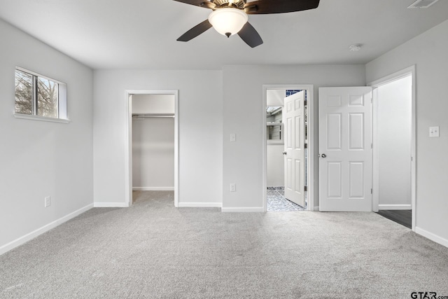 unfurnished bedroom with baseboards, a ceiling fan, carpet, a spacious closet, and a closet