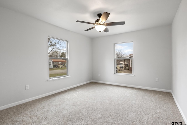 carpeted empty room with baseboards and a ceiling fan