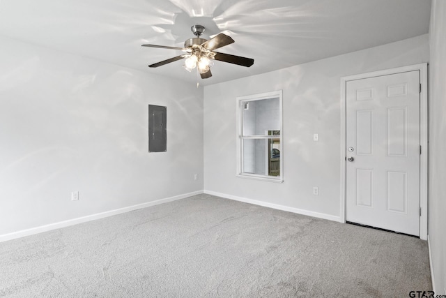 carpeted empty room with a ceiling fan, electric panel, and baseboards