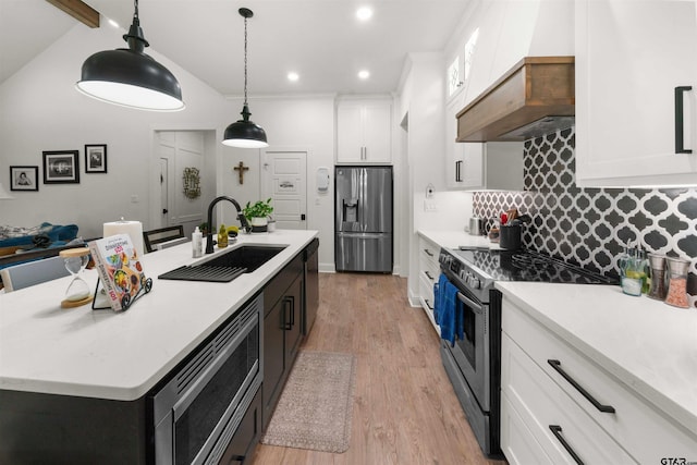 kitchen with white cabinetry, sink, hanging light fixtures, stainless steel appliances, and a kitchen island with sink