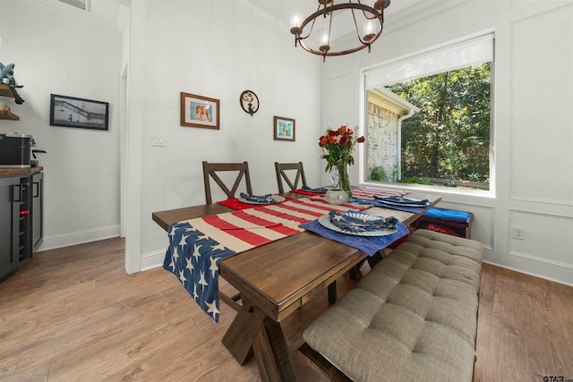 dining space with an inviting chandelier, ornamental molding, and light hardwood / wood-style flooring