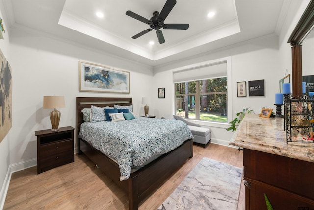 bedroom with ceiling fan, light hardwood / wood-style floors, a raised ceiling, and crown molding