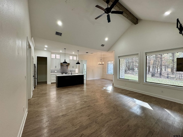 unfurnished living room featuring beamed ceiling, ceiling fan with notable chandelier, dark hardwood / wood-style floors, and high vaulted ceiling