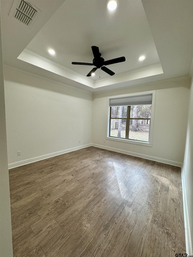 empty room featuring wood-type flooring, a tray ceiling, ceiling fan, and crown molding