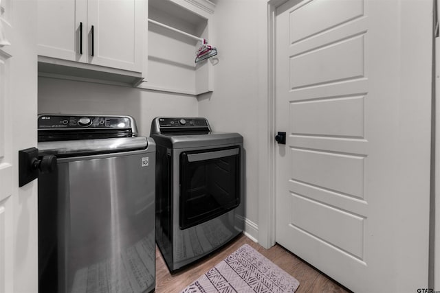 laundry area featuring hardwood / wood-style floors, washer and clothes dryer, and cabinets