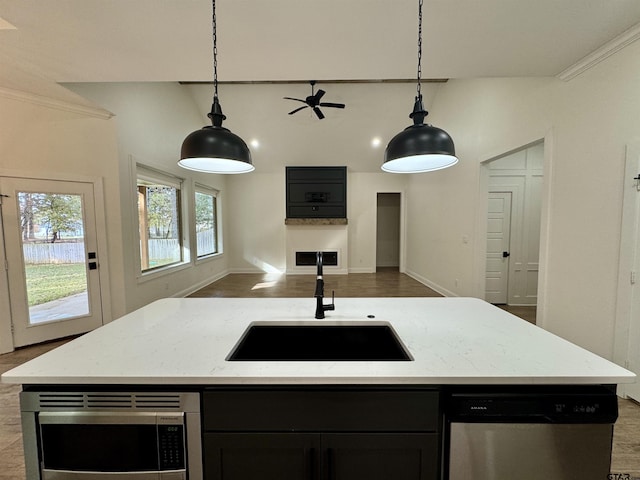 kitchen with an island with sink, stainless steel appliances, hanging light fixtures, and sink