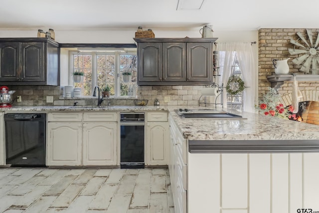 kitchen featuring black dishwasher, sink, decorative backsplash, and a wealth of natural light