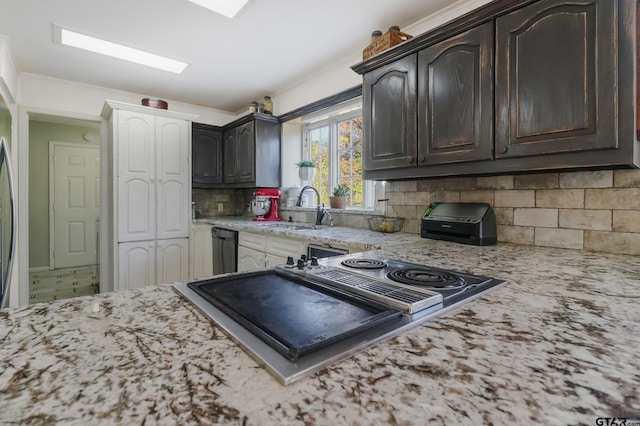 kitchen featuring dark brown cabinetry, sink, tasteful backsplash, light stone counters, and black dishwasher