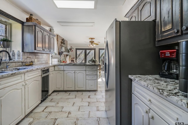 kitchen featuring sink, backsplash, stainless steel fridge, and a healthy amount of sunlight