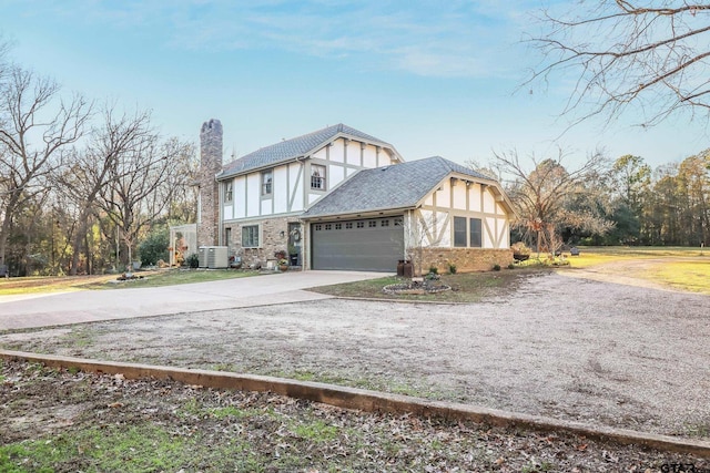 tudor-style house featuring a garage and central AC unit