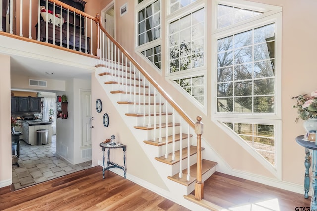 stairs with wood-type flooring and a high ceiling