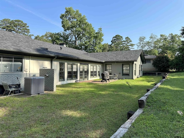 rear view of property featuring central AC and a yard
