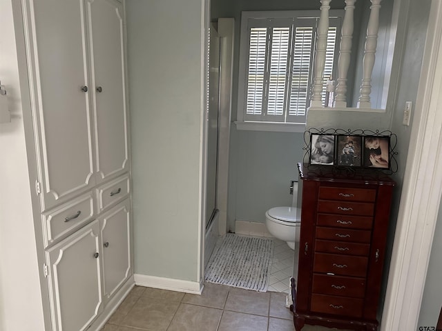 bathroom with toilet, a shower with door, and tile patterned floors