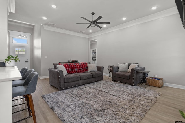 living room featuring ceiling fan with notable chandelier, light hardwood / wood-style flooring, and ornamental molding