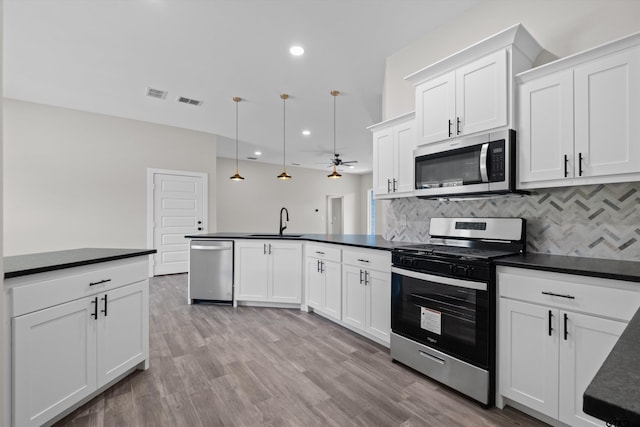 kitchen with sink, white cabinets, hanging light fixtures, and stainless steel appliances