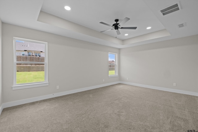 unfurnished room with ceiling fan, carpet, and a tray ceiling