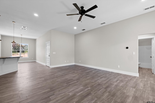 unfurnished living room with ceiling fan with notable chandelier and dark hardwood / wood-style floors