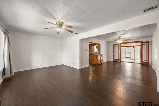 unfurnished living room with ceiling fan, dark hardwood / wood-style floors, and a textured ceiling