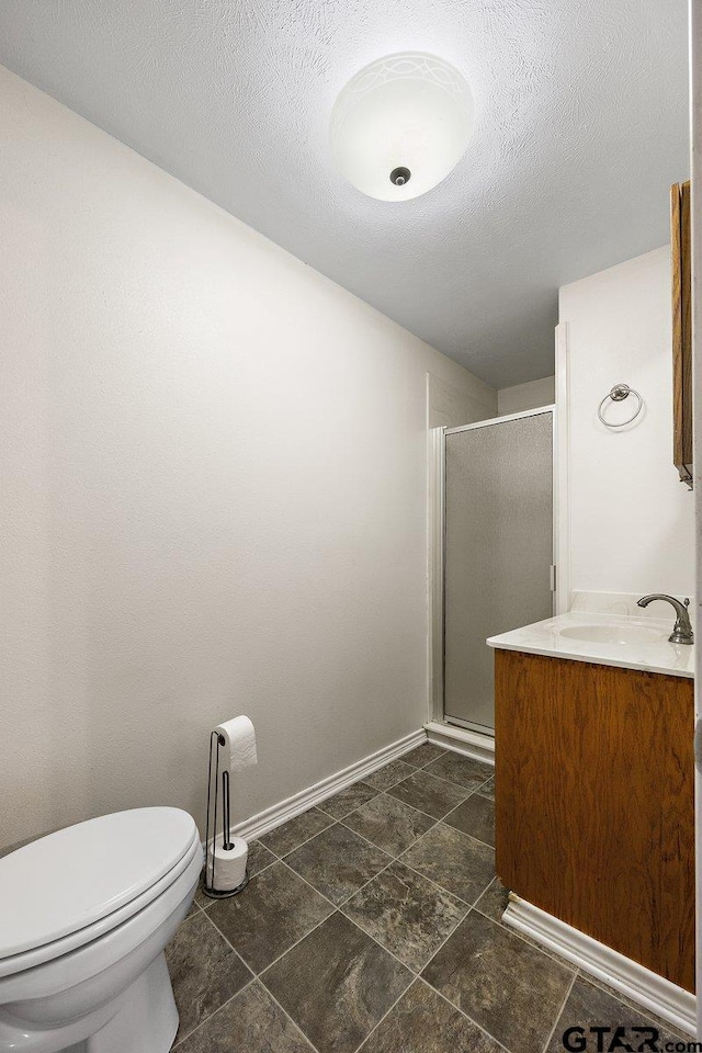 bathroom featuring vanity, a textured ceiling, a shower with door, and toilet