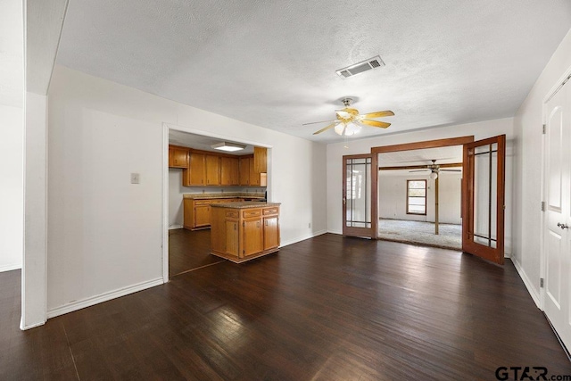 unfurnished living room featuring ceiling fan, a textured ceiling, and dark hardwood / wood-style flooring