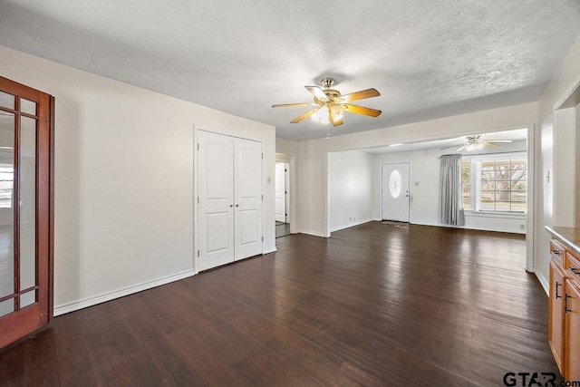 unfurnished living room featuring ceiling fan, dark hardwood / wood-style floors, and a textured ceiling