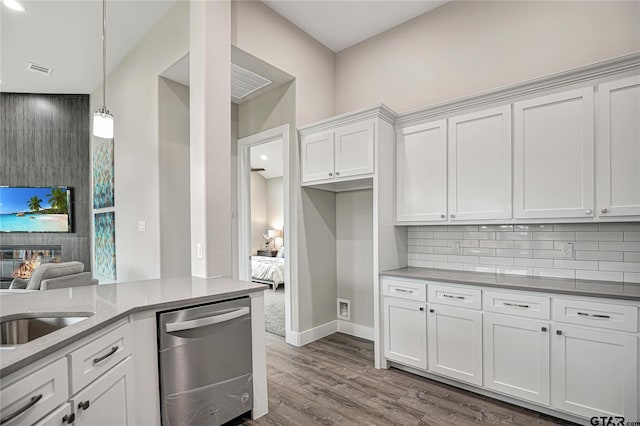 kitchen with white cabinetry, dishwasher, tasteful backsplash, a fireplace, and hardwood / wood-style flooring