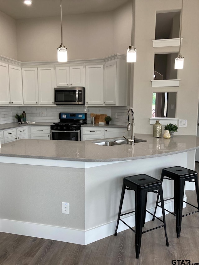 kitchen with sink, dark hardwood / wood-style floors, appliances with stainless steel finishes, a kitchen bar, and white cabinetry