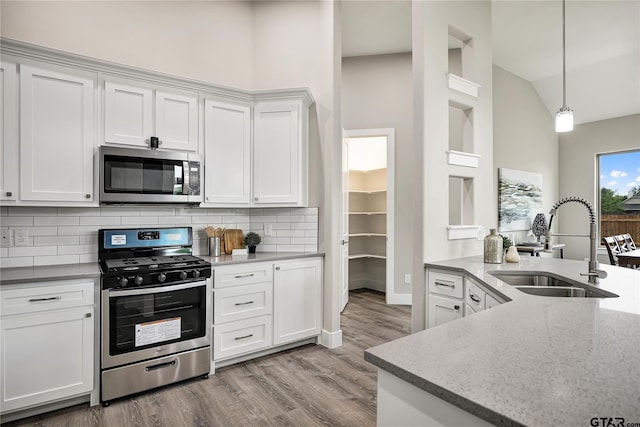 kitchen featuring appliances with stainless steel finishes, white cabinetry, hanging light fixtures, and sink