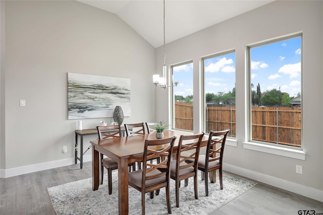 dining room featuring a notable chandelier, light wood-type flooring, and lofted ceiling