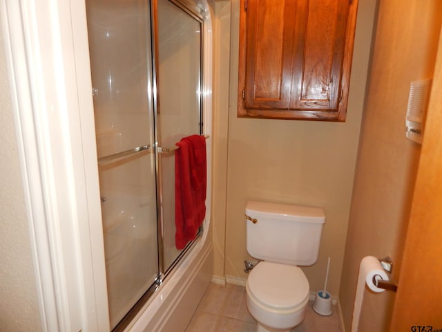 bathroom featuring toilet, tile patterned floors, and combined bath / shower with glass door