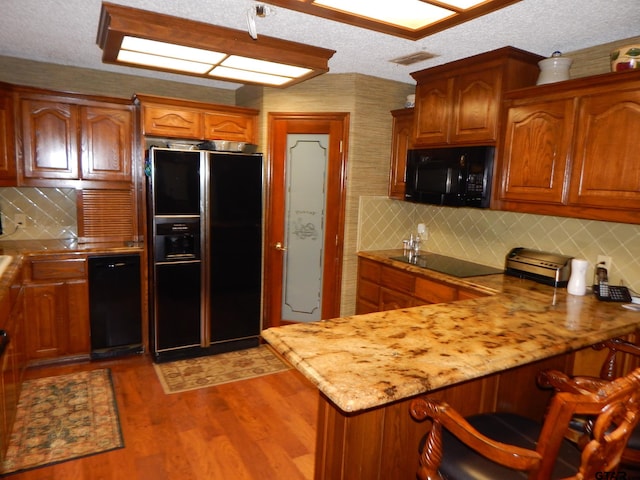 kitchen with black appliances, dark hardwood / wood-style floors, light stone countertops, a textured ceiling, and tasteful backsplash