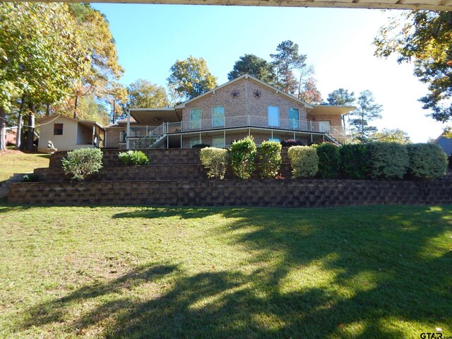 3073 E Lake Lake, Gladewater, TX 75647 - rear view of house with brick siding, a yard, and stairs