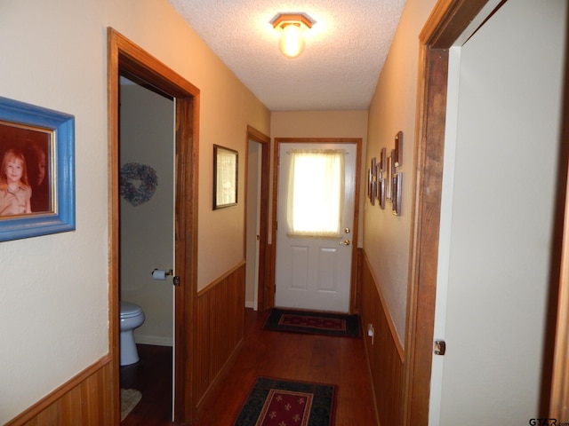 doorway to outside featuring wooden walls, dark hardwood / wood-style floors, and a textured ceiling