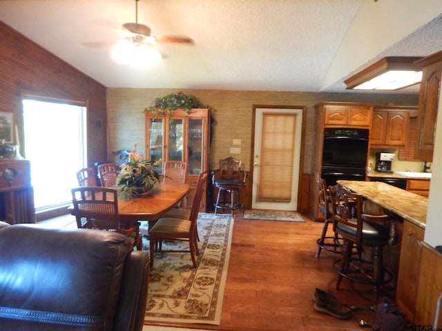 dining room with ceiling fan, light hardwood / wood-style floors, and lofted ceiling