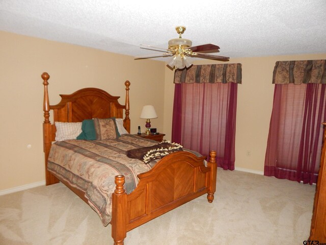 carpeted bedroom featuring ceiling fan and a textured ceiling