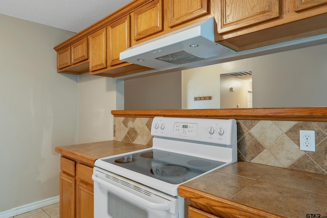 kitchen featuring a textured ceiling, backsplash, tile counters, and electric range