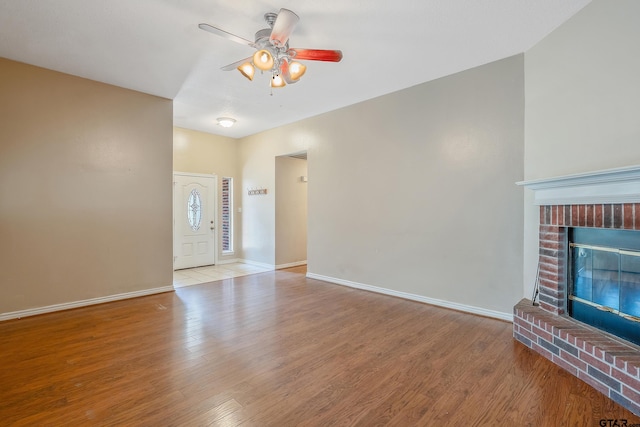 unfurnished living room with light wood-type flooring, ceiling fan, and a fireplace