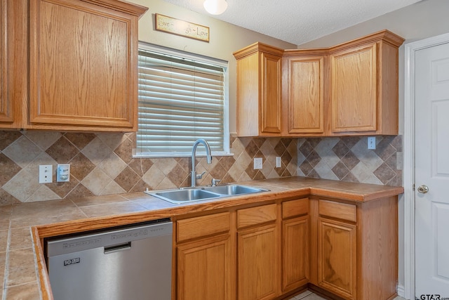 kitchen featuring tile counters, a textured ceiling, sink, stainless steel dishwasher, and backsplash