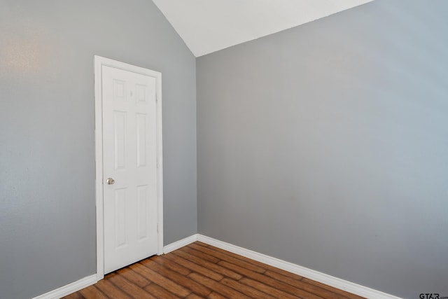 spare room featuring dark hardwood / wood-style floors and vaulted ceiling