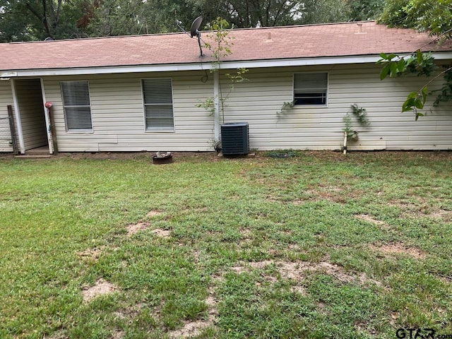 rear view of house with cooling unit and a lawn