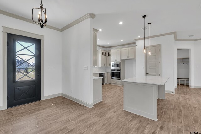 entrance foyer with ornamental molding, light wood-type flooring, and an inviting chandelier