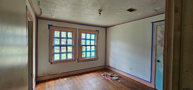 empty room featuring wood-type flooring and a textured ceiling