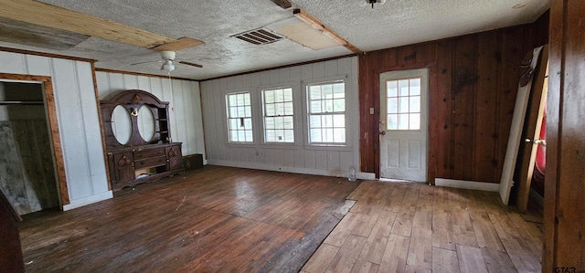 interior space with hardwood / wood-style floors, ceiling fan, wood walls, and a textured ceiling