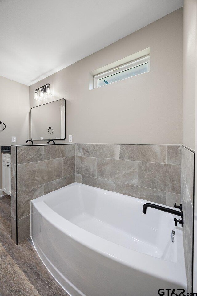 437 Tara Ln, Troup, TX 75789 - full bathroom featuring wood finished floors, a garden tub, and vanity