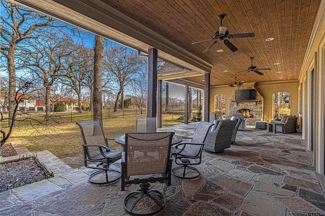 view of patio with ceiling fan and an outdoor stone fireplace