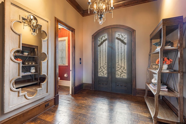 foyer with a notable chandelier, french doors, crown molding, and dark wood-type flooring