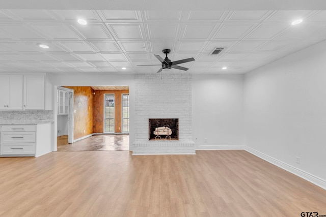 unfurnished living room featuring a brick fireplace, ceiling fan, and light wood-type flooring