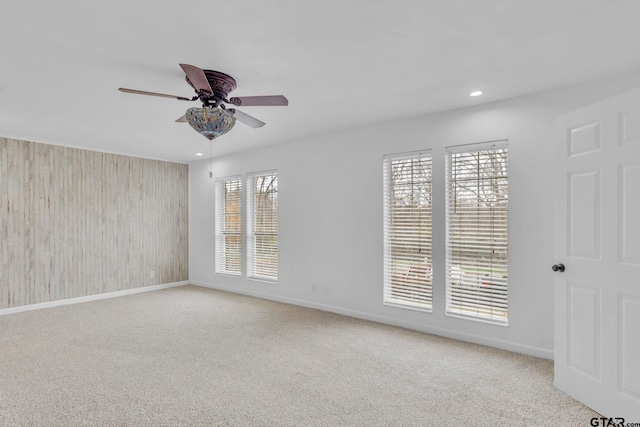 carpeted spare room featuring a wealth of natural light and ceiling fan