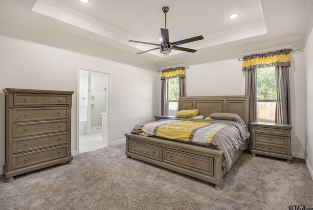 bedroom featuring a tray ceiling, light colored carpet, ceiling fan, crown molding, and connected bathroom